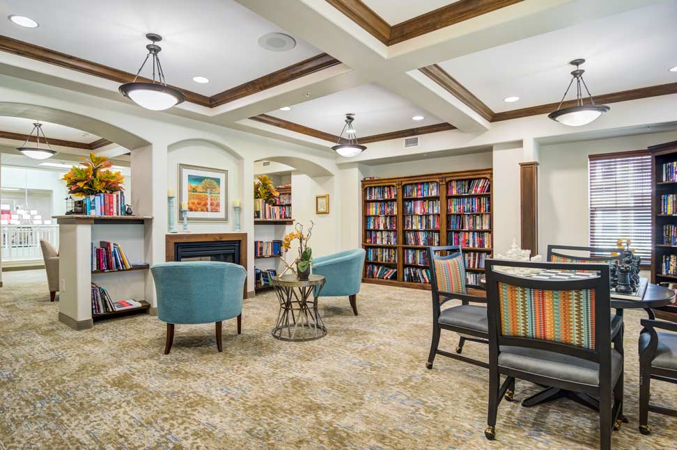 The library at Cottonwood Estates with shelves of books and comfortable seating