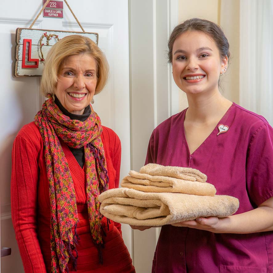 A team member delivering fresh linens to a resident at Cottonwood Estates